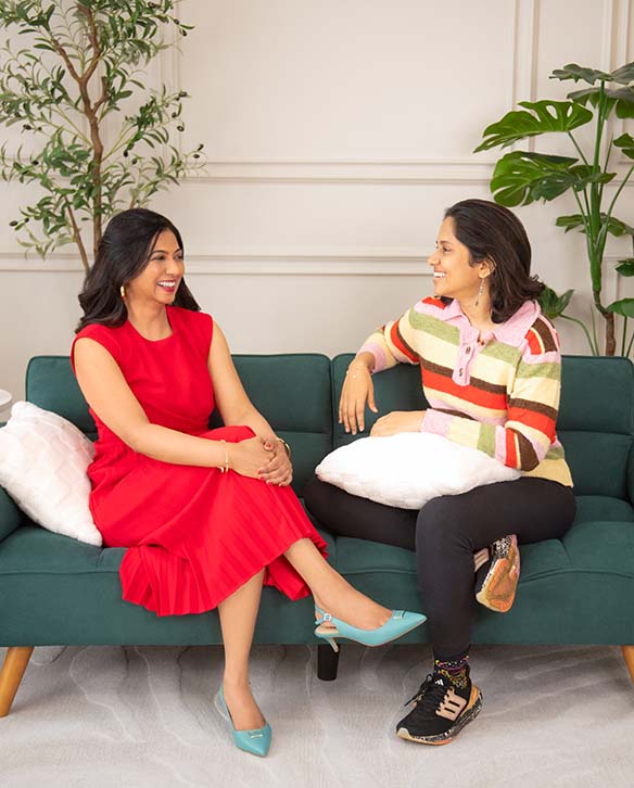 Two women smiling and talking together on a sofa